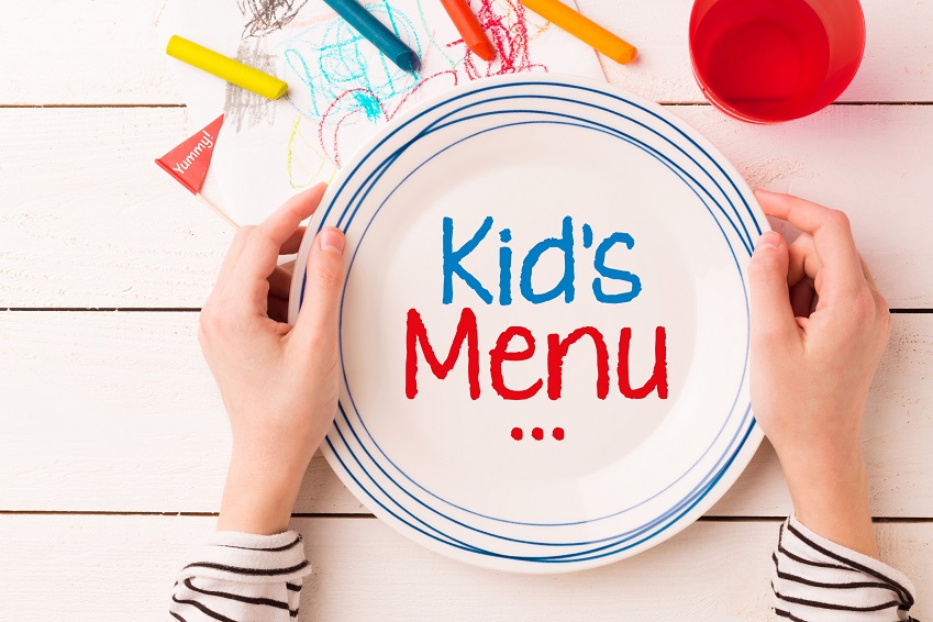 Plate with 'Kid's Menu' sign in child's hands